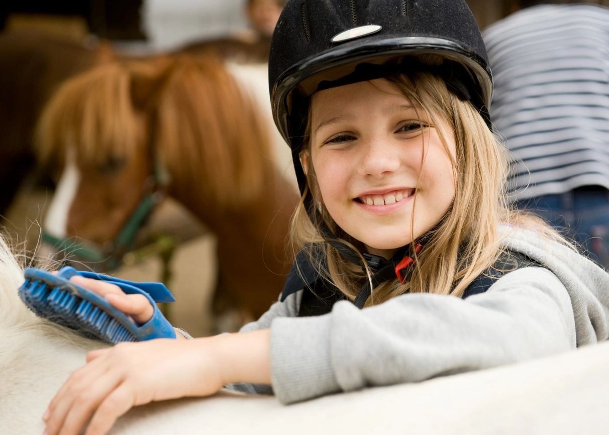 A little girl wearing a helmet and smiling.